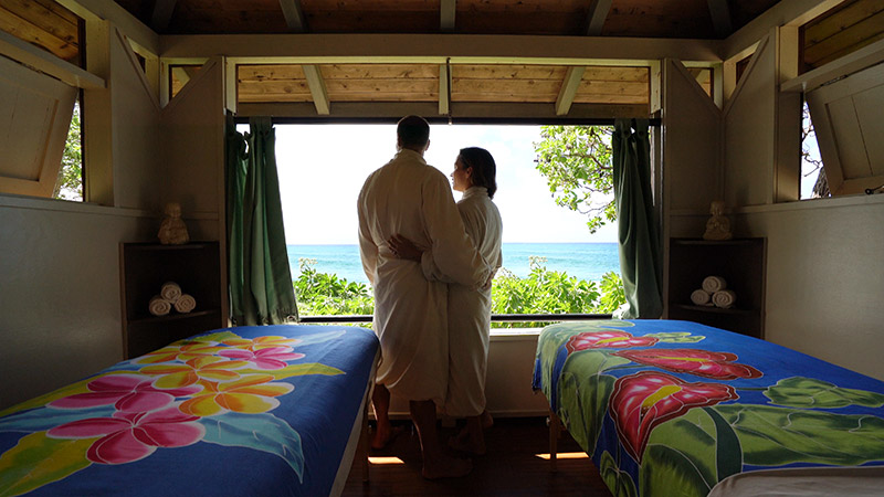 A couple in robes next to matching massage tables