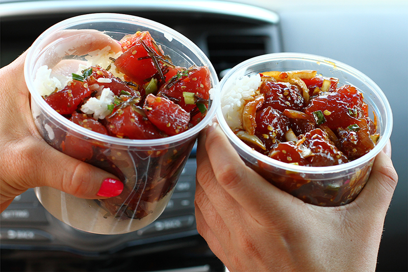 Two people toasting plastic cups filled with raw fish