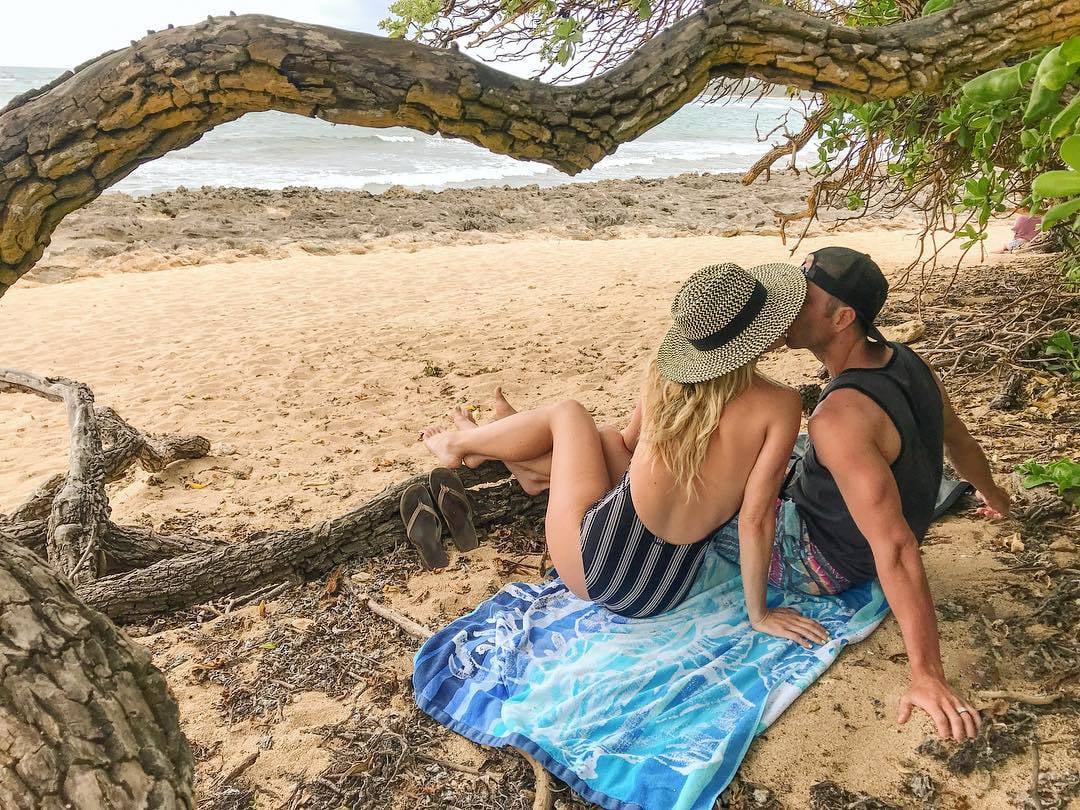 A couple on the beach kissing under a tree