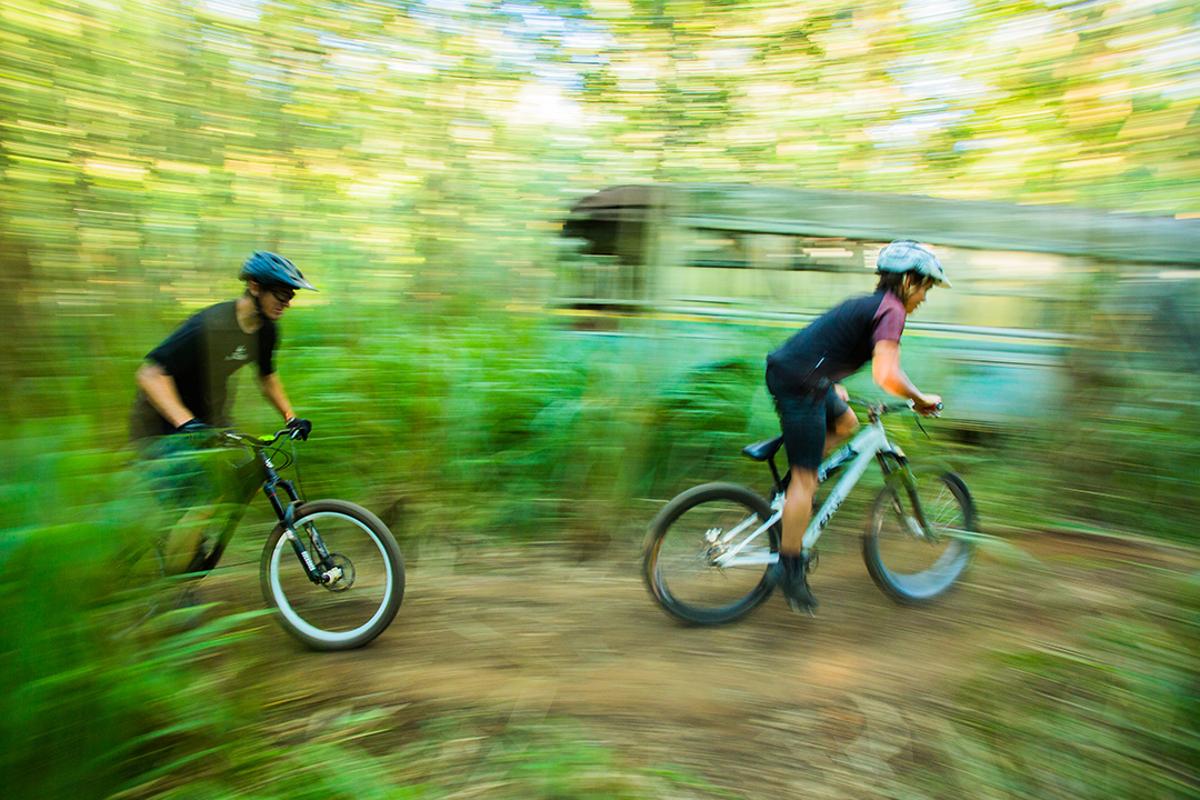 Two men racing on bicycles through the woods