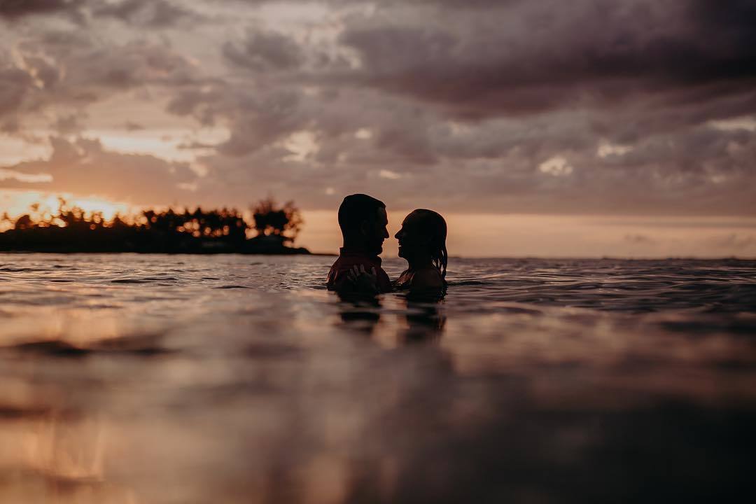 A silhouette of a couple face to face in the ocean at sunset