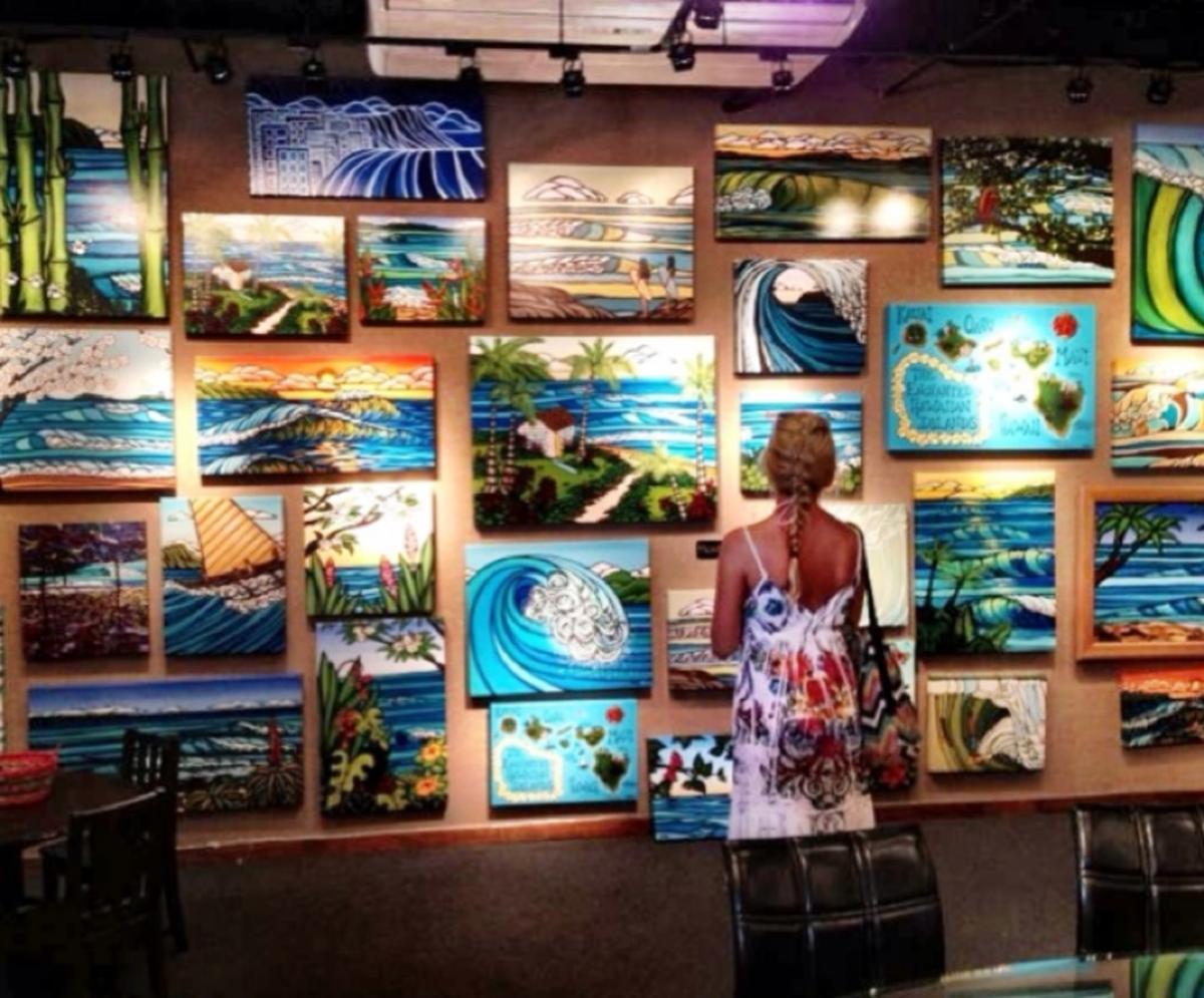 A woman standing in front of a wall of paintings