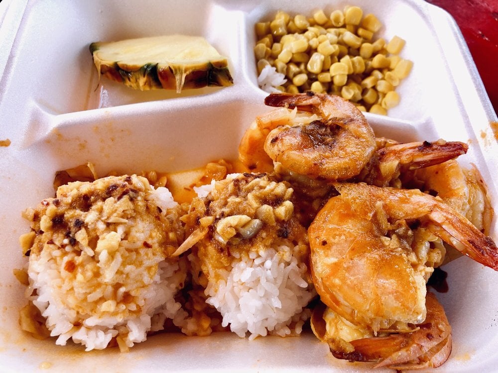 A take-out container with rice, seafood, and corn