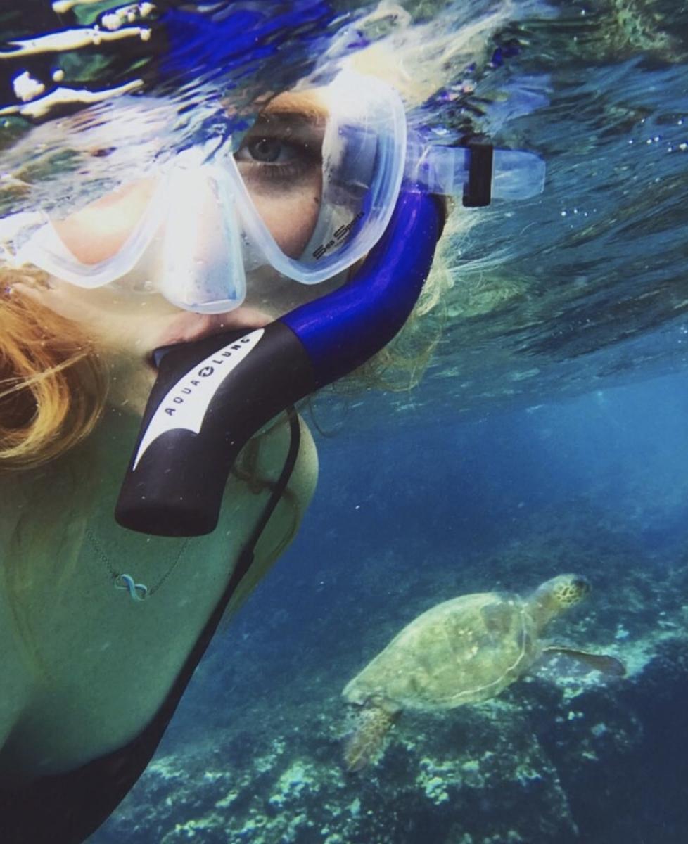 A woman snorkling near a sea turtle