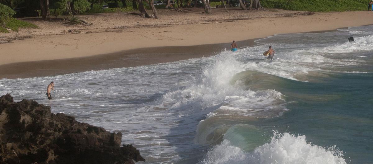 People wading in the ocean off Pounders Beach, Oahu