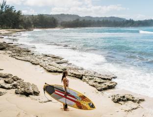 Woman holding a surf board by the ocean