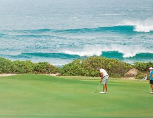 Two Golfers on a lush green course overlooking the ocean