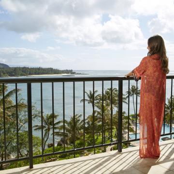 Woman standing on a balcony overlooking the ocean