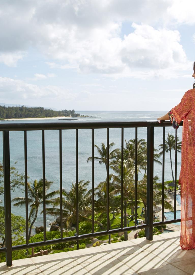 Woman standing on a balcony overlooking the ocean