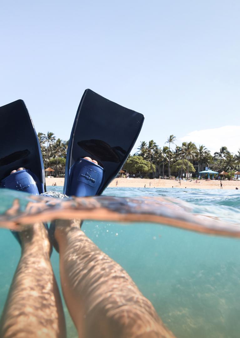 A snorkler's POV of his feet floating in the ocean