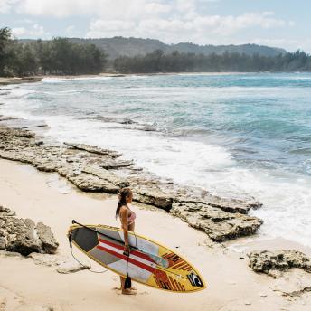 Woman holding a surf board by the ocean